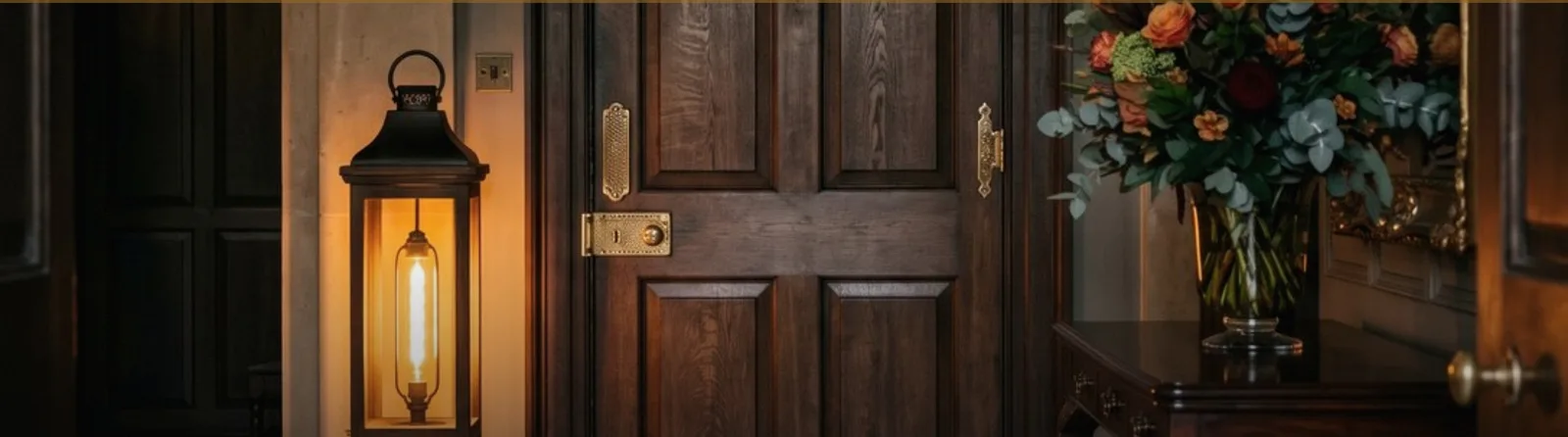 A lantern lit beside the panelled front door of a private residence